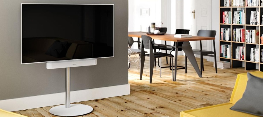 Televisor blanco sobre un soporte blanco con una barra de sonido blanca en el salón.